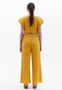 Ensemble jaune texturé en deux pièces comprenant un haut court à manches courtes et un pantalon large à taille élastique.