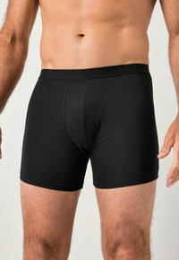 Pánské černé boxerky z hladké látky. Mají krátké nohavice, volný střih a pas s nenápadným logem.