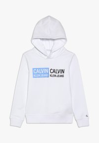 Biała bluza z kapturem wykonana z mieszanki bawełny, z nadrukiem na froncie w czarnym i niebieskim kolorze, z napisem "CALVIN KLEIN JEANS" na wysokości klatki piersiowej.
