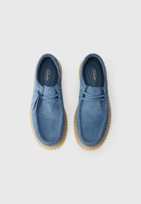 Pair of blue suede casual shoes with gum soles and laces, viewed from above on a white background.