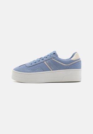 Baskets basses en daim bleu clair avec des accents blancs et une semelle épaisse blanche, vues de côté.