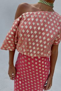 Rosa off-shoulder topp med gullprikker, kombinert med et skjørt med samme design. Mykt stoff med en flytende silhuett.