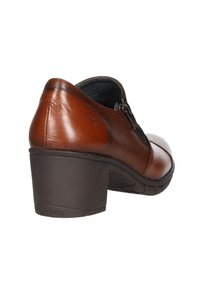 Zapato de tacón de cuero marrón con puntera redondeada, superficie texturizada y cremallera lateral para facilitar su uso. Tacón ligero y suela flexible.