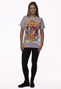 Light purple cotton t-shirt featuring a colorful "Yellow Submarine" graphic with The Beatles characters, paired with black skinny jeans and shoes.
