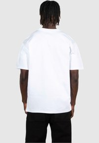T-shirt bianco in cotone con una vestibilità comoda, maniche corte e scollatura rotonda, visto da dietro. Texture liscia e dettagli minimi.
