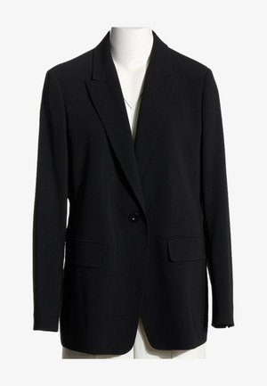 Blazer noir à un seul bouton avec revers crantés et poches à rabat, présenté sur un torse de mannequin blanc sur fond blanc.