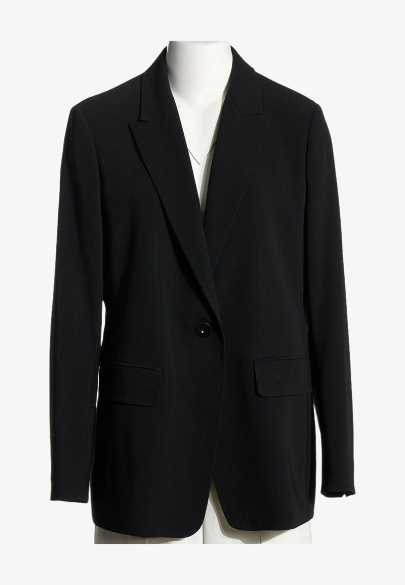 Blazer noir à un seul bouton avec revers crantés et poches à rabat, présenté sur un torse de mannequin blanc sur fond blanc.