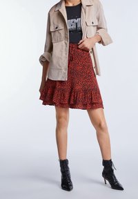 Punainen leopardikuvioinen hame, jossa on röyhelöhelma, yhdistetty mustaan graafiseen T-paitaan ja vaaleanbeigeen pitkään hihaan. Mustat nauhattomat korkokengät.