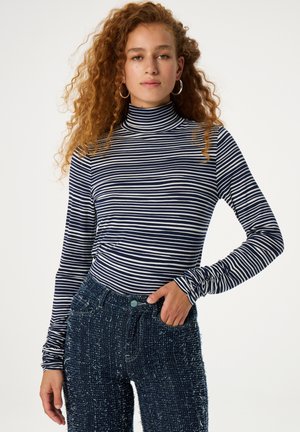 Marineblauwe en witte gestreepte lange mouwen coltrui van zacht materiaal, gecombineerd met gestructureerde donkerblauwe broek.
