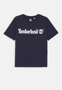 Camiseta de algodón azul marino con mangas cortas, con logo blanco de "Timberland" y gráfico de árbol en el frente, cuello redondo.