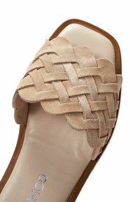Beige mockasin sandal i mocka med en vävd ovandel, rund tå och en slät läderinnersula med en brun yttersula.