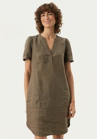 Olivengrünes Leinenkleid mit kurzen Ärmeln und V-Ausschnitt, mit lässigem Schnitt, Seitentaschen und subtiler Textur für zusätzliche Details.