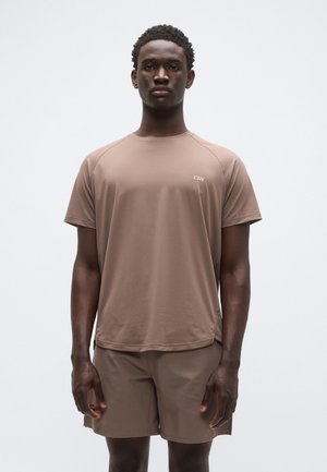 Brun kortermet treningsskjorte med raglanermer, lett stoff, subtil logo, kombinert med matchende shorts i matt finish.