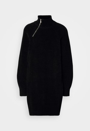 Robes-pulls noir en maille avec un col haut, un détail de fermeture éclair unique et des manches longues légèrement bouffantes. Ourlets et poignets à côtes. Texture douce.