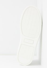 Semelle de basket blanche avec un motif ondulé texturé, forme plate et un petit logo en relief sur la section du talon. Matériau en caoutchouc lisse.