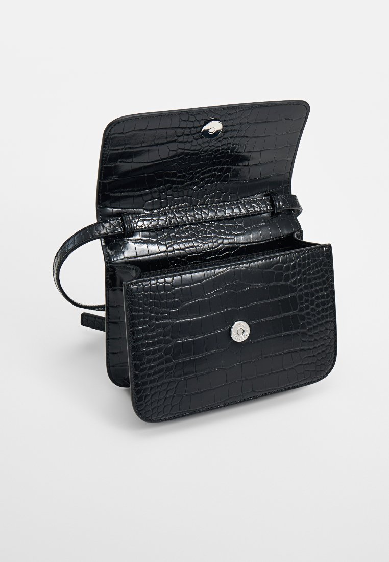 Czarna torebka typu crossbody z czarnej skóry o fakturze krokodyla, z otwartą klapą i srebrnym zapięciem, ukazująca wnętrze z przegrodami.