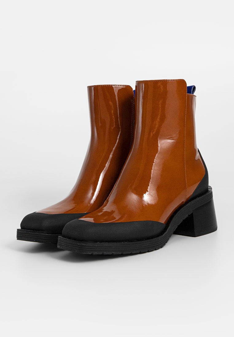 Braune hochglänzende Stiefeletten mit einer schwarzen Gummikappe und Ferse. Verfügt über einen Blockabsatz und eine glatte Oberfläche. Gefüttert in Blau.