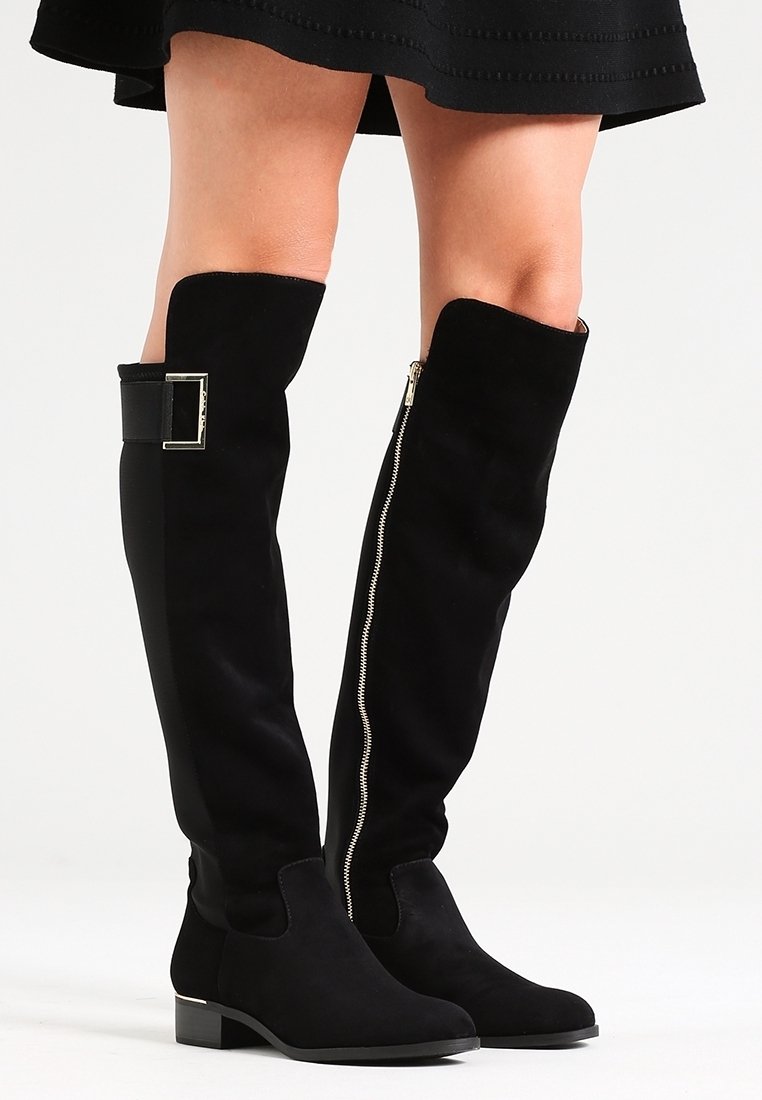 Black suede over-the-knee boots feature a side zipper and buckle detail. The shaft is smooth with a flat sole for easy wear.