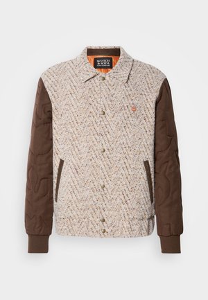 Giacca con bottoni, davanti in tessuto beige e marrone a trama, maniche trapuntate marroni scure, polsini a costine e due tasche anteriori.