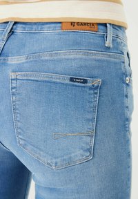 Helle blaue Jeans aus Denim mit kontrastierender, brauner Naht. Mit einem Lederpatch mit der Aufschrift "GARCI A" am Bund und einem kleinen Logo auf der hinteren Tasche.