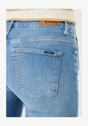 Lichtblauwe denim jeans met contrasterende tan stiksels. Heeft een leren label met de tekst "GARCI A" op de tailleband en een klein logo op de achterzak.