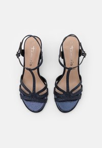 Paire de sandales bleu marine à brides avec boucles à la cheville, orteils ouverts et semelles intérieures beiges marquées taille 37 et texte de marque.