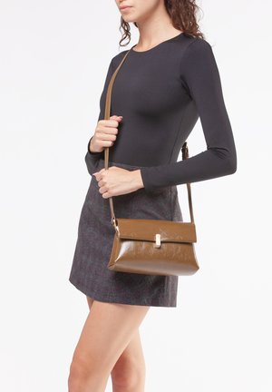 Brun faux læder crossbody taske med klap og metalhardware, der har en glat tekstur og en rektangulær form.