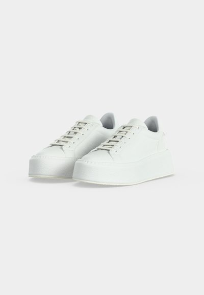 Baskets à plateforme blanches avec semelles épaisses et lacets, placées côte à côte sur un fond clair uni.