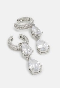 Boucles d'oreilles en argent avec deux pierres transparentes en forme de goutte suspendues à un anneau texturé avec des accents pavés.