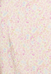 Tejido de crema suave con un patrón floral en pequeños tonos de rosa, púrpura y azul claro disperso. Costura ligera visible en el lado izquierdo.