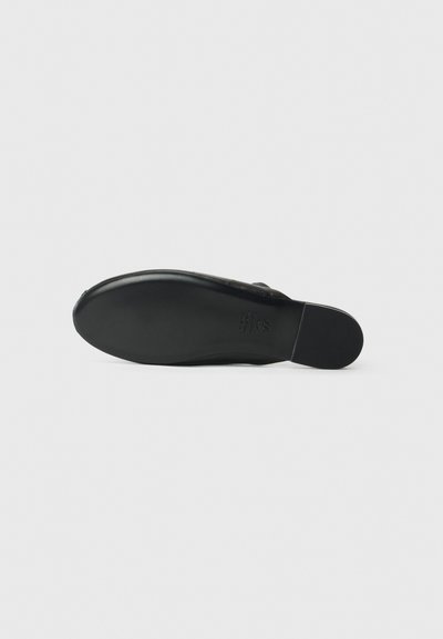 Black flat shoe sole with a smooth texture, slightly curved shape, and a rounded toe. Includes embossed brand detail on the bottom.
