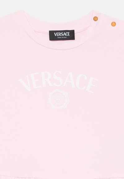 T-shirt de algodão cor-de-rosa com o logo branco "VERSACE" e gráfico de Medusa, com dois botões de pressão dourados no ombro.