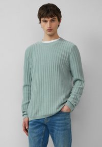 Jasnoniebieski sweter prążkowany z długimi rękawami, okrągłym dekoltem i teksturowanym wykończeniem, w połączeniu z dżinsami. Standardowy krój i casualowy styl.