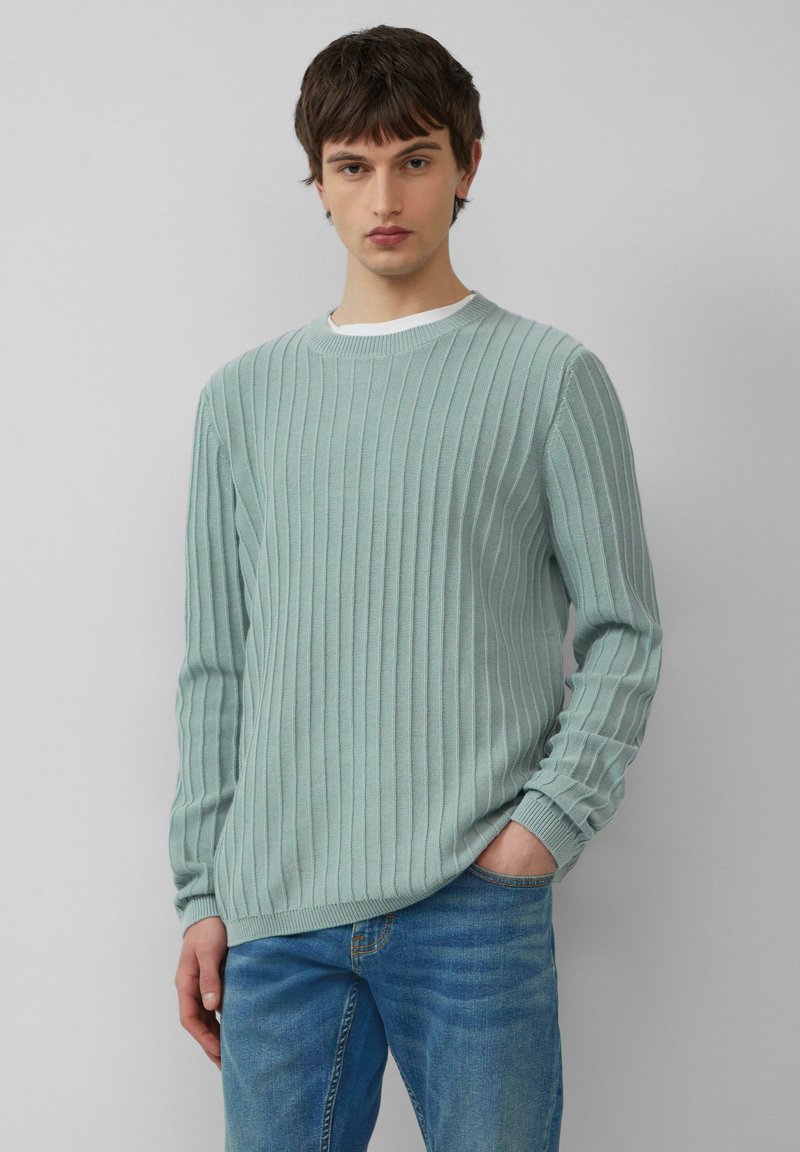 Jasnoniebieski sweter prążkowany z długimi rękawami, okrągłym dekoltem i teksturowanym wykończeniem, w połączeniu z dżinsami. Standardowy krój i casualowy styl.