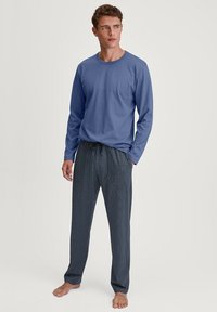 Camicia di cotone blu a maniche lunghe abbinata a pantaloni da pigiama navy con motivo a pois bianchi e vita elasticizzata.