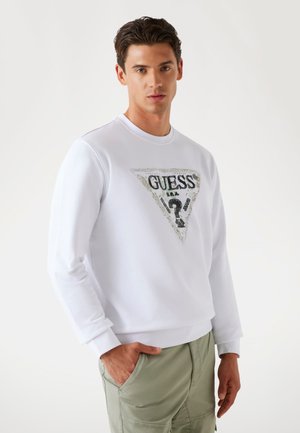 White sweatshirt with a triangular graphic design featuring the text "GUESS" in black, accented with green and silver details.