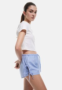 Witte cropped t-shirt met textuurdetails, gecombineerd met lichtblauwe geruite shorts met een elastische tailleband en trekkoord.