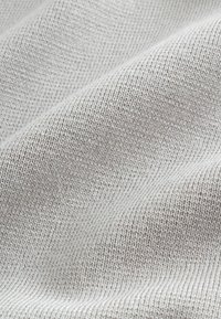 Tejido gris claro con una textura suave, que presenta un patrón de punto fino y uniforme y un ligero brillo, cayendo suavemente en ondas.