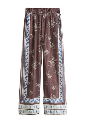 Pantalones anchos marrones con dibujo lineal blanco de hojas, cerámica y olas, bordeados en azul y blanco con nombres de islas griegas en el dobladillo.