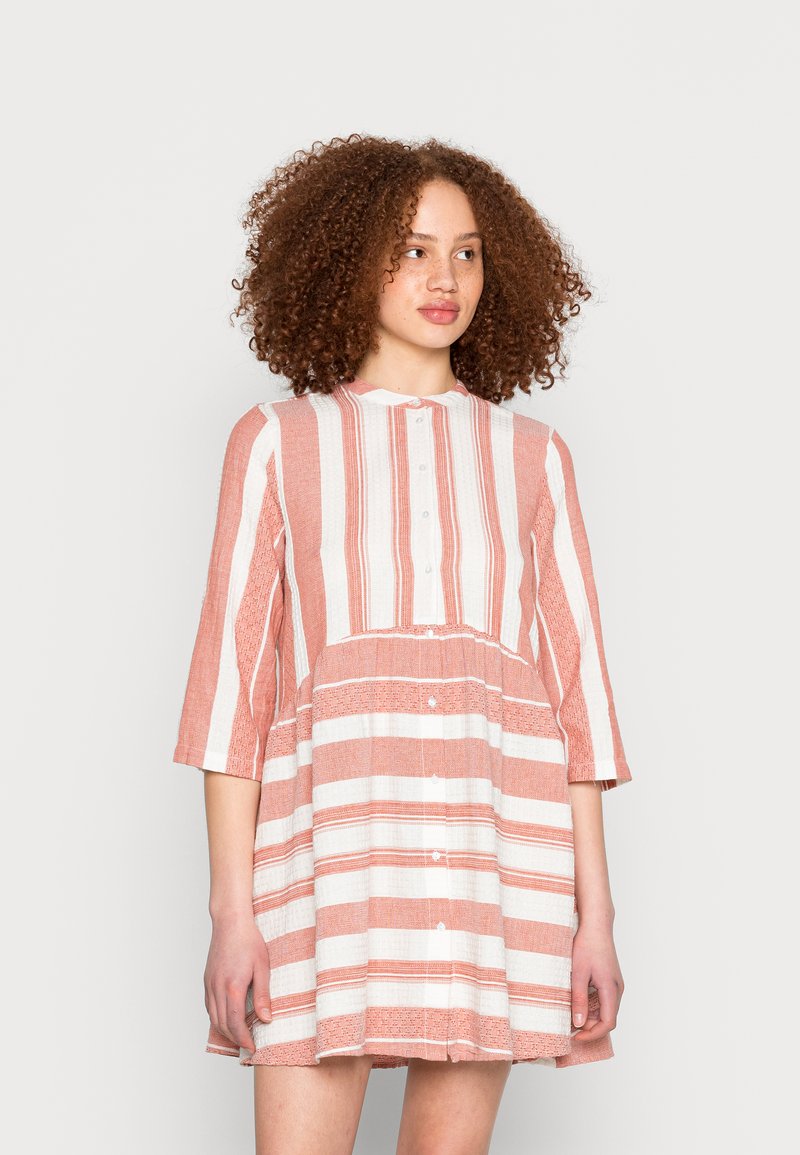 Vestido às riscas em terracota e branco, com um fecho frontal de botões, mangas 3/4 e uma saia em camadas com tecido texturizado.