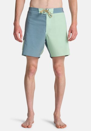 Costume da bagno da uomo in azzurro e verde menta, con tasca laterale, chiusura con coulisse e pannelli in tessuto a contrasto.