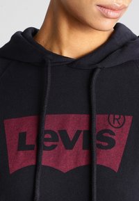 Černá bavlněná mikina s kapucí s červeným grafikem loga Levis a šňůrkami. Měkká textura s volným střihem.