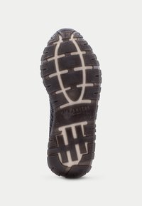 Semelle de chaussure en caoutchouc noir avec un design texturé et multi-motif pour une meilleure adhérence, accompagnée d'une semelle intermédiaire de couleur claire et d'un logo de marque embossé sur le talon.