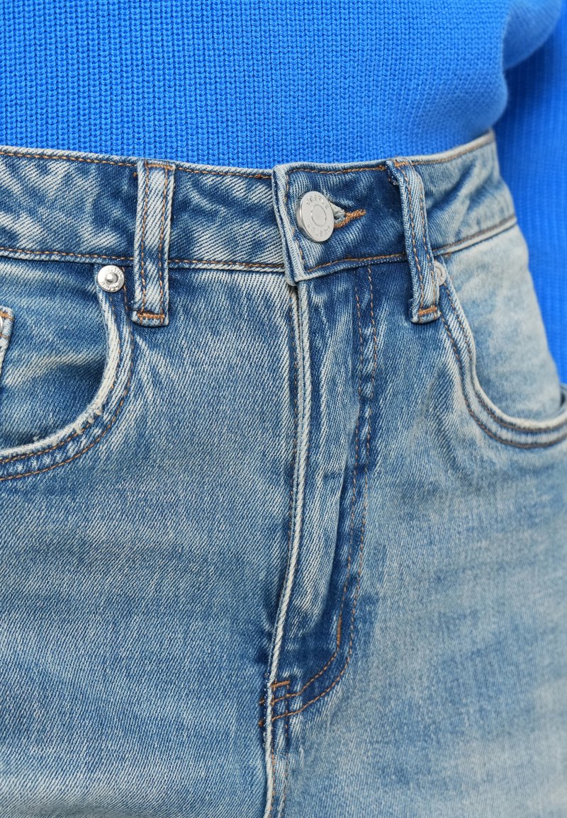 Jeans di denim azzurro chiaro con aree sbiadite, design a cinque tasche, chiusura con bottone in metallo e cuciture a contrasto. Tessuto di cotone strutturato.