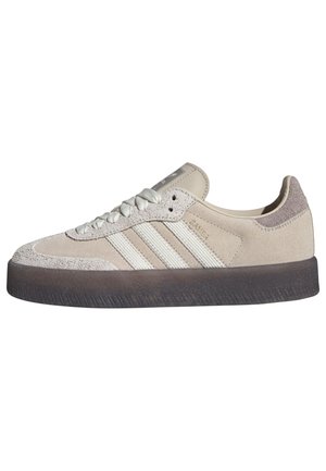 Beige mokkasinsneaker med lavt snit, hvide snørebånd, hvide tre-stribede detaljer og en tyk mørkegrå sål.