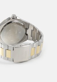 Edelstahl-Armbanduhr mit einem silbernen und goldenen zweifarbigen Armband, rechteckigen Gliedern und einem polierten Metallschluss, ausgestattet mit einem runden Gehäuseboden.