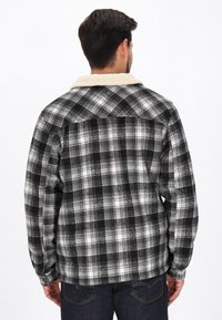 Czarna, szara i biała flanelowa kurtka w kratę z kremowym kołnierzem z owczej wełny. Posiada luźny krój i długie rękawy. Teksturowana tkanina.