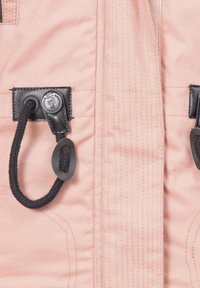 Pink textile with black hardware, featuring drawstrings and a logo patch, highlighting a smooth texture and fine stitching details.
