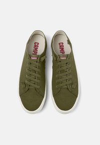 Sneakers in tela verde oliva con suole bianche in gomma, dotate di lacci e con il logo "CAMPER" in rosso sulla soletta.