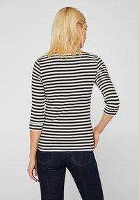Mustavalkoraidallinen pitkähihainen t-paita, jossa on pyöreä kaula-aukko ja vartalonmyötäinen muotoilu. Paidassa on kolme neljännestä hihaa ja suora helma.